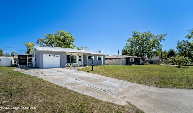 ranch-style house with fence, concrete driveway, a front yard, metal roof, and an attached garage