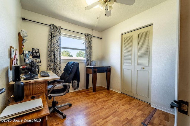 office with a ceiling fan, wood finished floors, a textured wall, and a textured ceiling