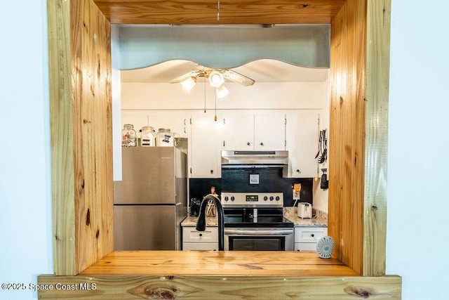 kitchen with butcher block countertops, stainless steel appliances, under cabinet range hood, white cabinetry, and backsplash