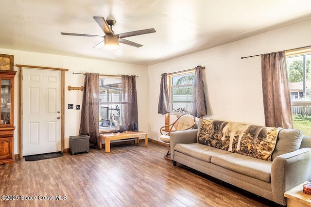 living room featuring a ceiling fan, wood finished floors, baseboards, and a healthy amount of sunlight