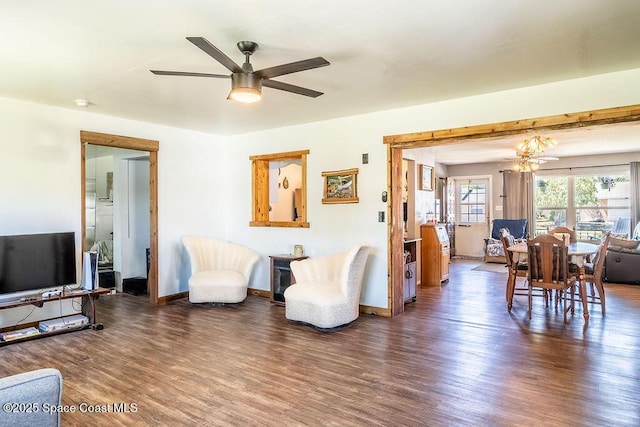 living area featuring ceiling fan with notable chandelier, baseboards, and wood finished floors