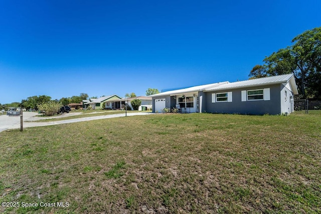 single story home with concrete driveway, a front yard, stucco siding, metal roof, and a garage