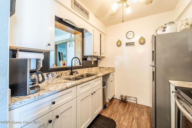 kitchen featuring a sink, light stone counters, wood finished floors, and white cabinets