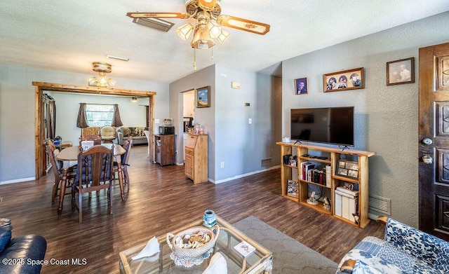 living area featuring wood finished floors, baseboards, visible vents, ceiling fan, and a textured ceiling