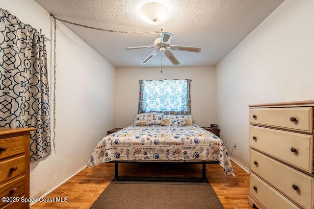 bedroom featuring light wood-style flooring, a ceiling fan, and a textured ceiling