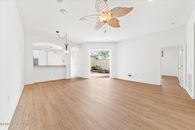 8652 Villanova Dr Unit 1001, Cape Canaveral, FL 32920 - unfurnished living room featuring ceiling fan, light wood-style floors, arched walkways, and baseboards