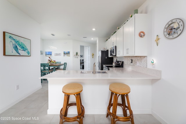 kitchen with a breakfast bar area, a peninsula, stainless steel appliances, and a sink