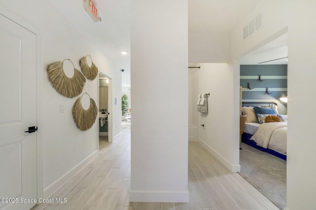 corridor featuring visible vents, baseboards, and wood finish floors