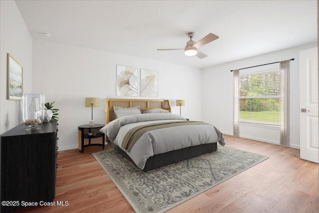 bedroom featuring light wood finished floors, a ceiling fan, and baseboards