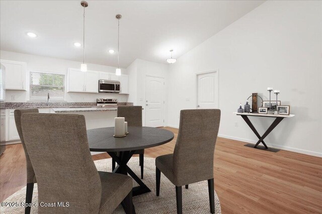 dining space with recessed lighting, baseboards, light wood finished floors, and high vaulted ceiling