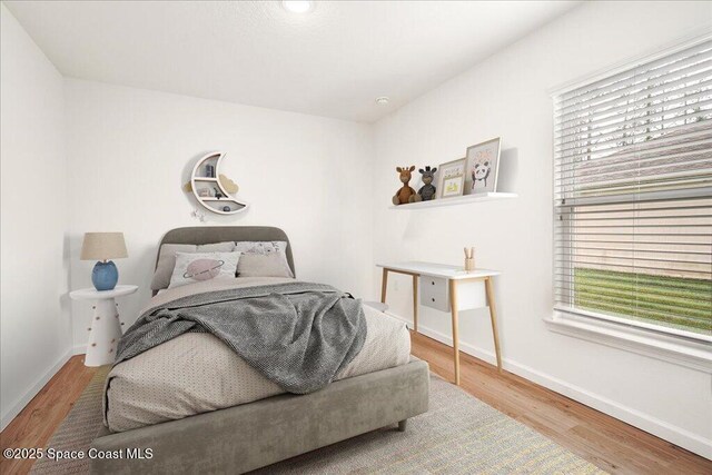 bedroom featuring baseboards, multiple windows, and wood finished floors
