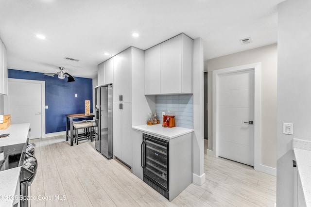 kitchen featuring visible vents, wine cooler, appliances with stainless steel finishes, white cabinets, and light countertops