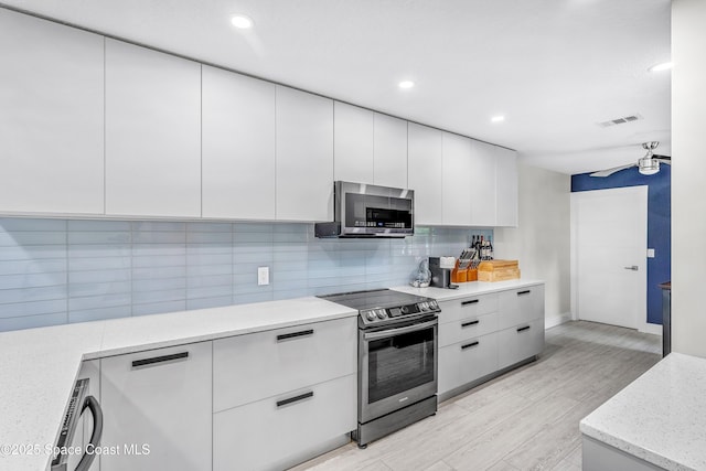 kitchen with visible vents, backsplash, appliances with stainless steel finishes, and modern cabinets