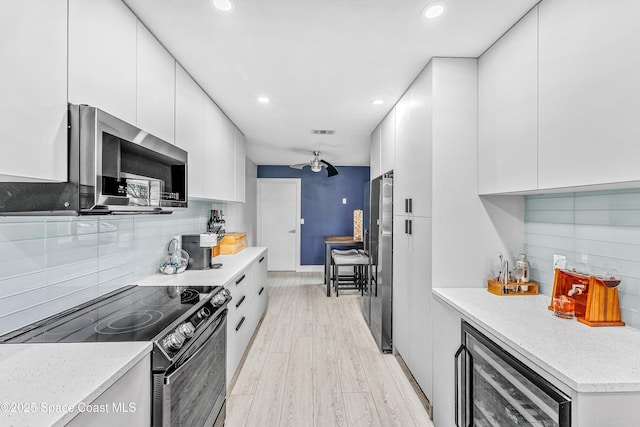 kitchen with stainless steel appliances, wine cooler, white cabinets, modern cabinets, and light wood-type flooring