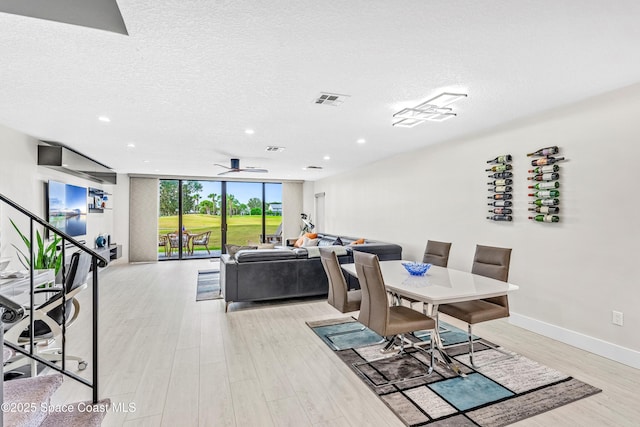 dining area with visible vents, a textured ceiling, floor to ceiling windows, light wood finished floors, and ceiling fan
