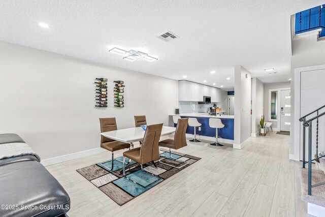 dining room featuring visible vents, light wood-type flooring, and baseboards
