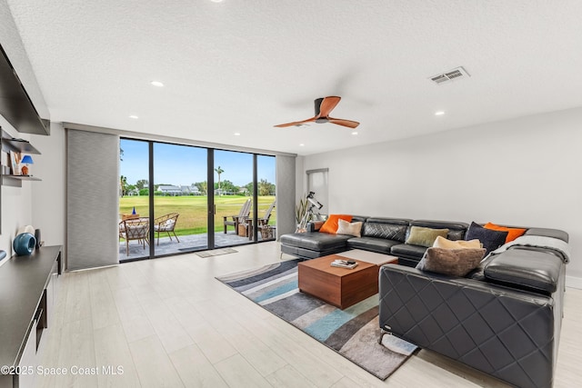 living area featuring visible vents, a ceiling fan, expansive windows, recessed lighting, and light wood finished floors