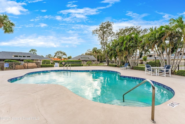 community pool with a patio area and fence