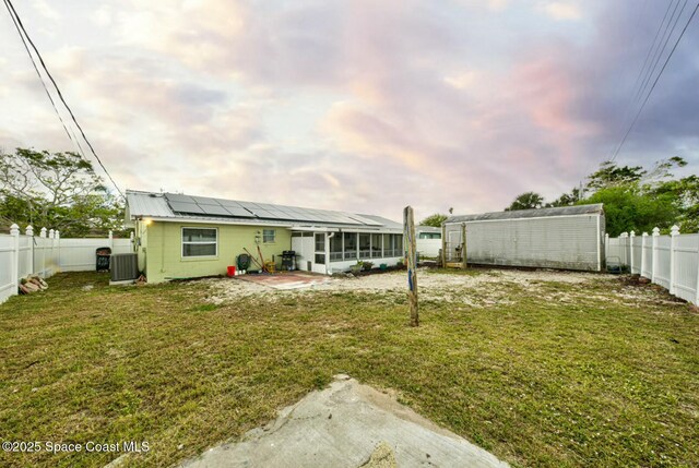 view of yard featuring a fenced backyard, cooling unit, a storage shed, an outdoor structure, and a sunroom