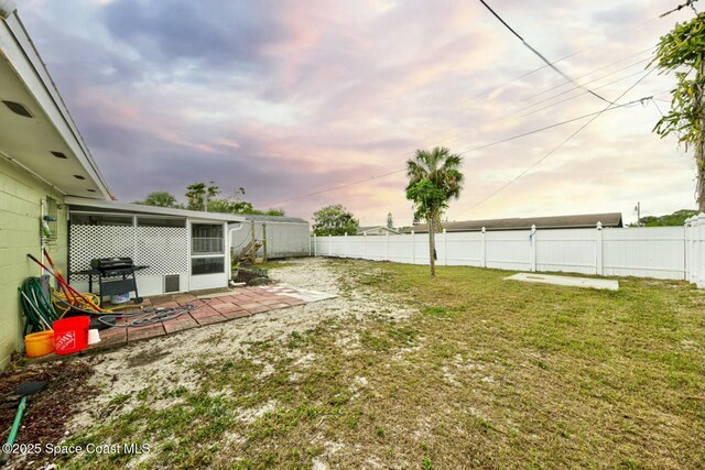 yard at dusk featuring a fenced backyard and a patio area