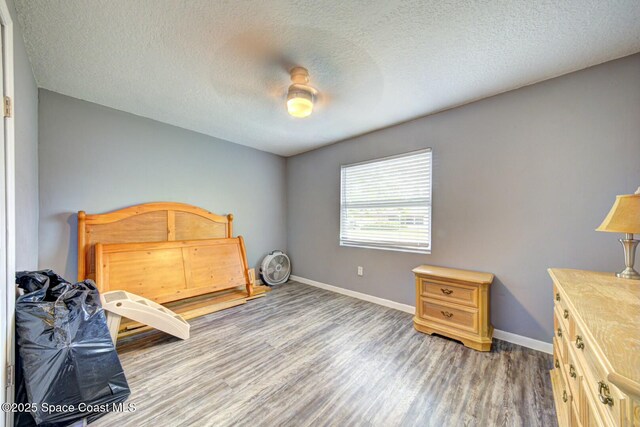 bedroom with ceiling fan, baseboards, a textured ceiling, and wood finished floors