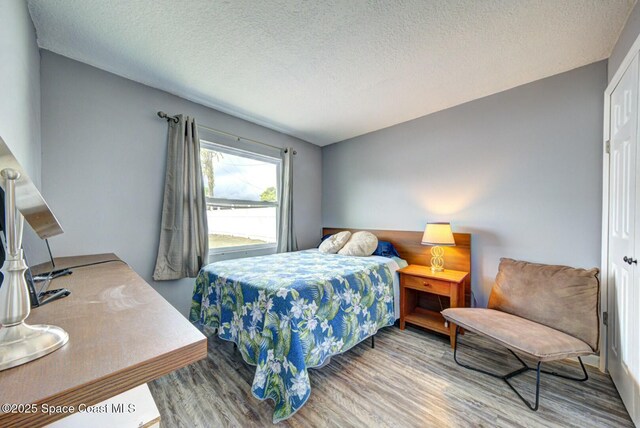 bedroom with a textured ceiling and wood finished floors