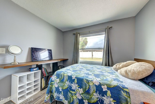 bedroom featuring wood finished floors and a textured ceiling