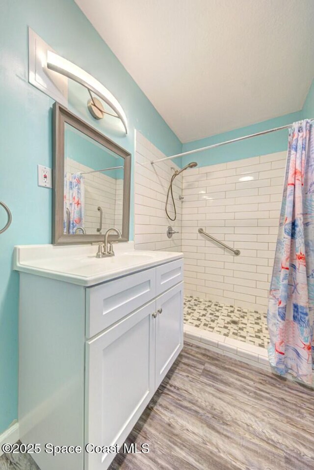 bathroom featuring vanity, wood finished floors, and a tile shower