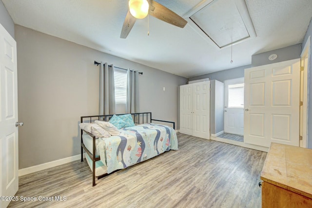bedroom featuring attic access, multiple windows, and wood finished floors