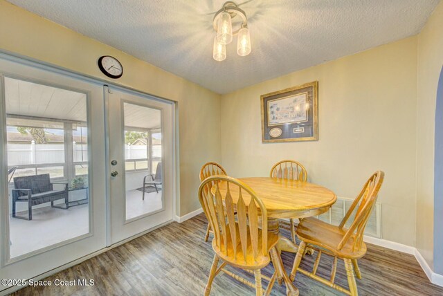 dining room with french doors, baseboards, a textured ceiling, and wood finished floors