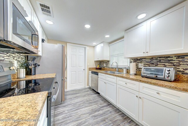 kitchen with visible vents, light wood-type flooring, a sink, white cabinetry, and appliances with stainless steel finishes