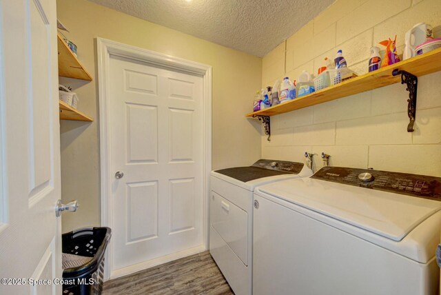 laundry area featuring laundry area, wood finished floors, independent washer and dryer, and a textured ceiling