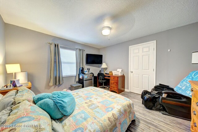 bedroom with a ceiling fan, wood finished floors, and a textured ceiling
