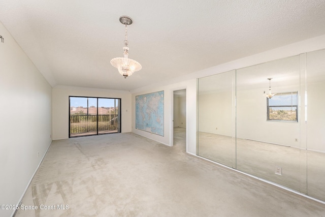 unfurnished bedroom featuring a closet, carpet floors, a textured ceiling, and a chandelier