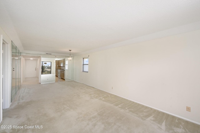 spare room with light colored carpet, visible vents, and a textured ceiling