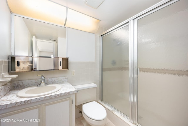 full bathroom featuring toilet, tile walls, a stall shower, and vanity