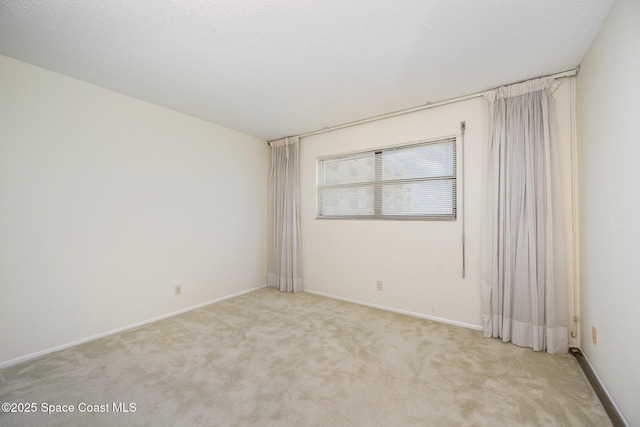 unfurnished room with baseboards, light carpet, and a textured ceiling