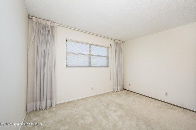 carpeted spare room featuring a textured ceiling and baseboards