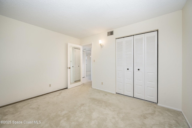 unfurnished bedroom with a closet, visible vents, a textured ceiling, and carpet