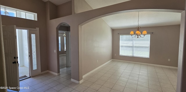 foyer with arched walkways, a notable chandelier, baseboards, and light tile patterned flooring