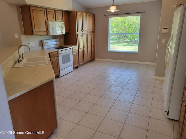 kitchen featuring white appliances, light tile patterned flooring, a sink, light countertops, and decorative light fixtures