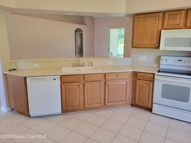 kitchen with white appliances, light countertops, arched walkways, and a sink