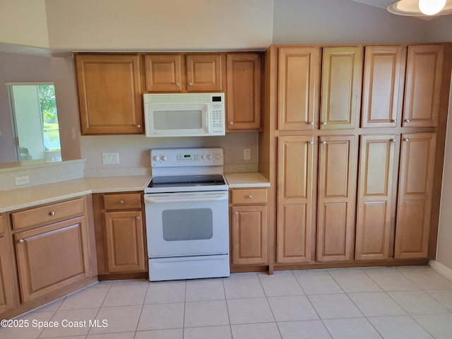 kitchen with light tile patterned floors, brown cabinetry, white appliances, and light countertops