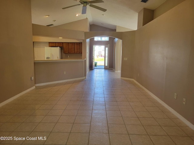 empty room featuring arched walkways, light tile patterned floors, baseboards, and ceiling fan