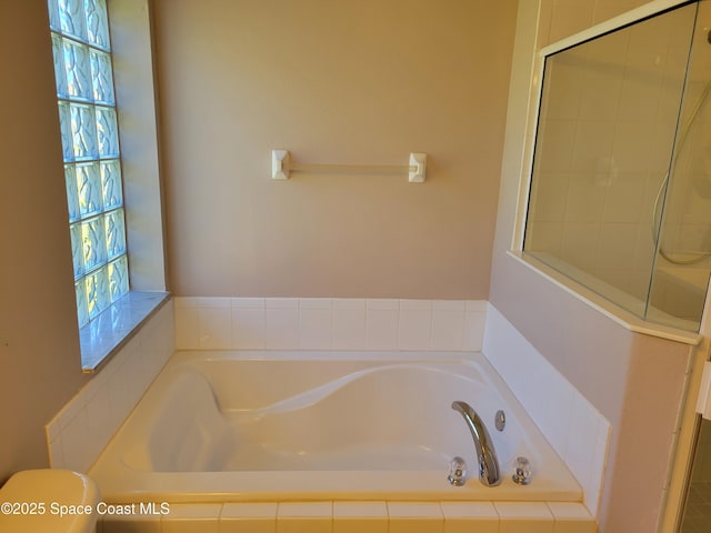 bathroom with a garden tub, toilet, and a tile shower