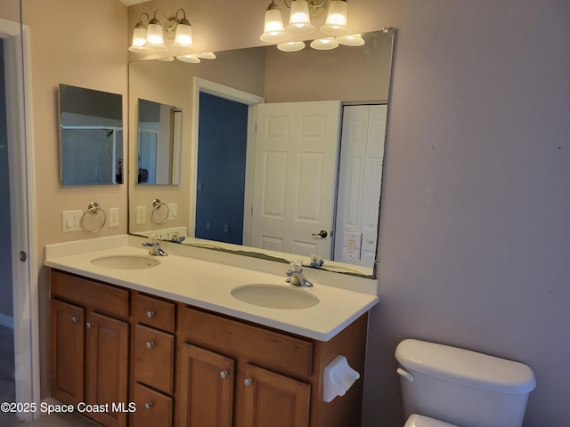 bathroom with double vanity, a chandelier, toilet, and a sink