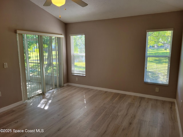 unfurnished room with baseboards, lofted ceiling, wood finished floors, and a ceiling fan