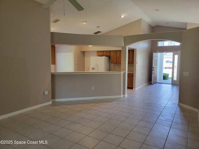unfurnished living room with visible vents, a ceiling fan, arched walkways, light tile patterned floors, and baseboards