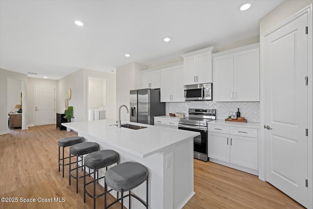 403 Fonsica St, Palm Bay, FL 32908 - kitchen featuring stainless steel appliances, a sink, a kitchen bar, an island with sink, and washer and clothes dryer