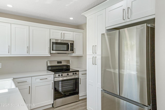 kitchen featuring light countertops, light wood finished floors, white cabinetry, stainless steel appliances, and recessed lighting